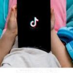 child holding phone with and displaying tiktok app